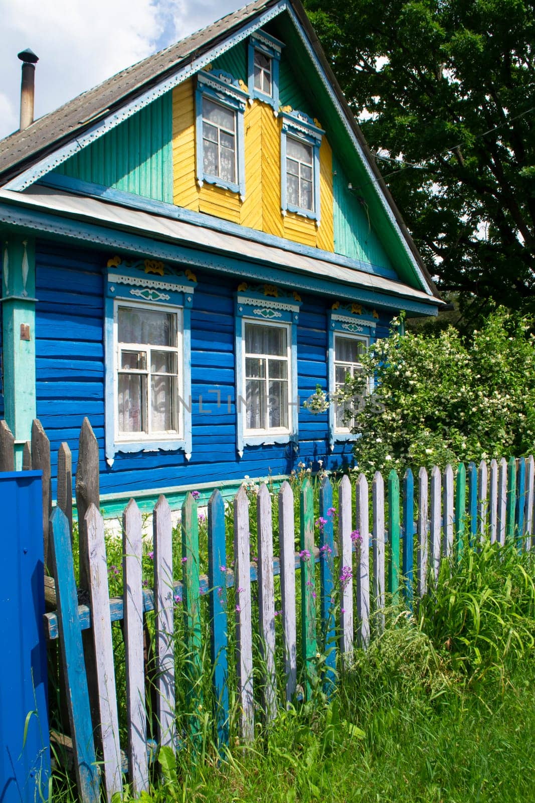 Traditional village house in Belarus. Windows with carved shutters and curtains. Vertical image