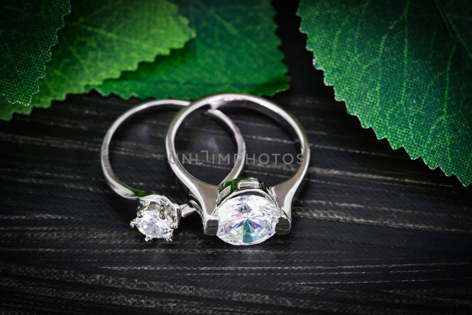 Close up Diamond gem wedding rings with green leaves on black background, Jewelry wedding diamond rings on black background