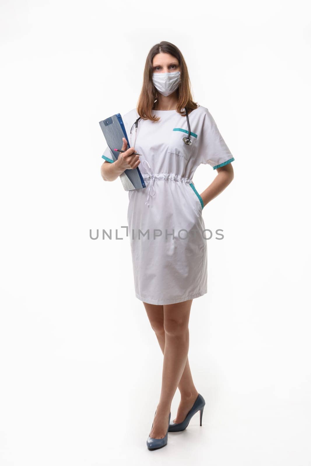 Girl in medical clothes and mask posing with tablet on white background
