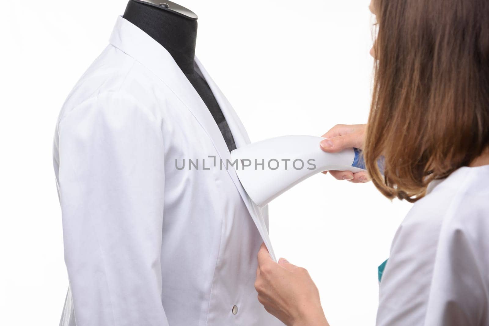 Girl handles medical clothing by steamer on a white background