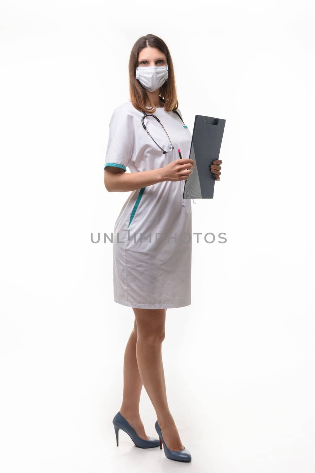 girl doctor in medical clothes and mask with tablet in hand on white background builds in full growth