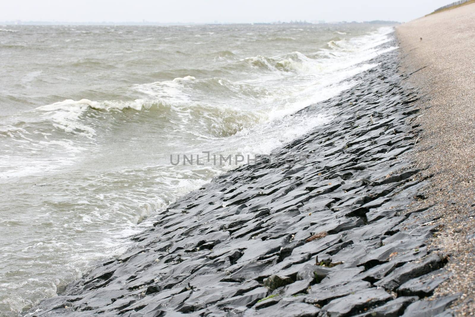 Detail view of a dam fortified with stones on the North Sea .