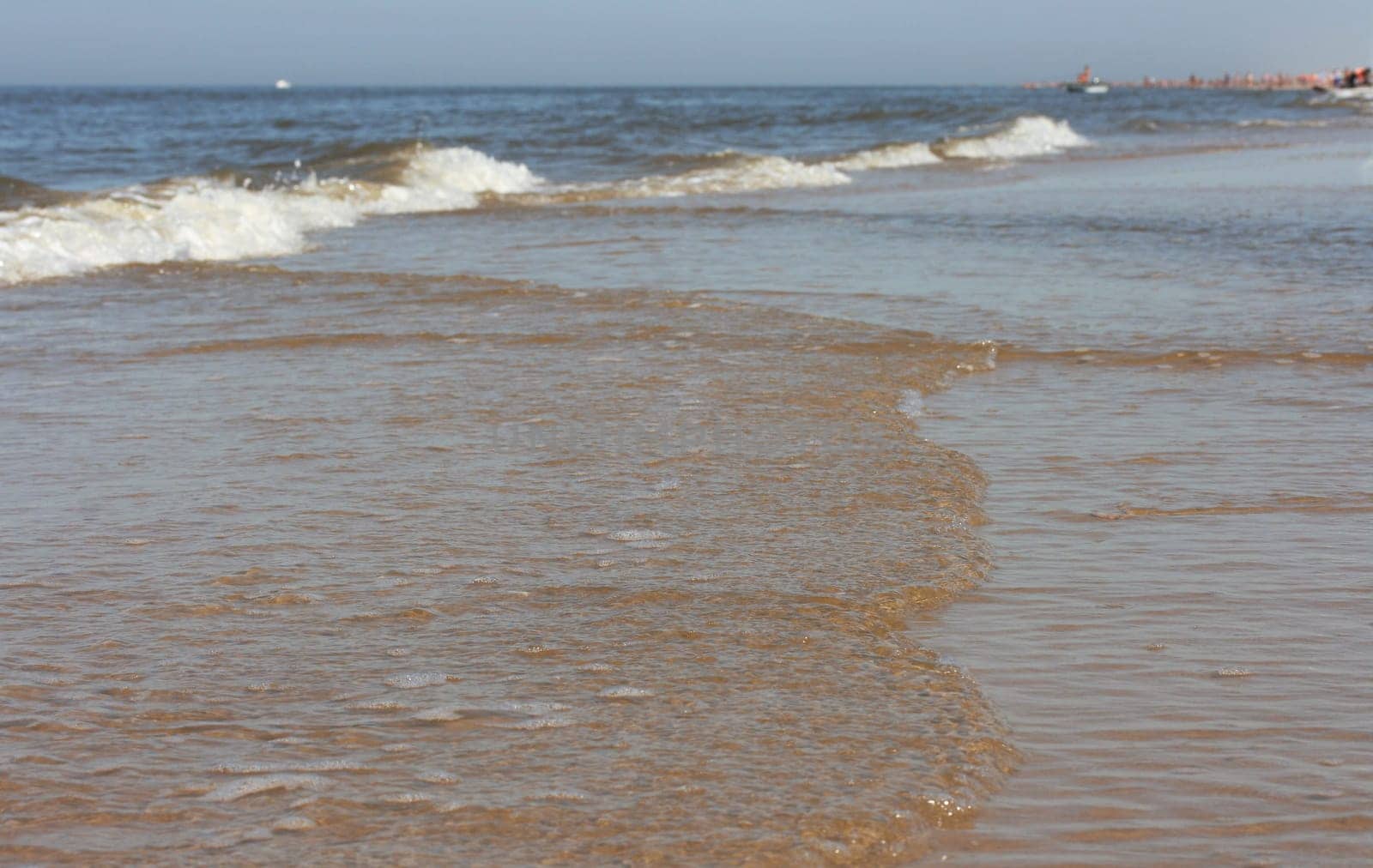 Waves with whitecaps flood the sandy beach.