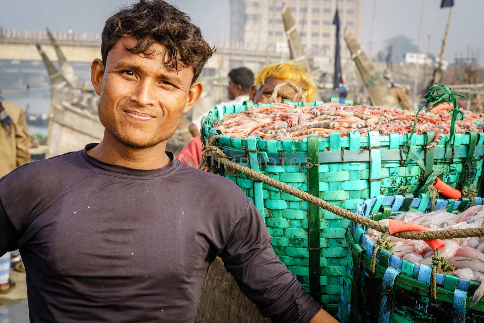 Chittagong, Bangladesh, December 23, 2017: Portrait of a fisherman next to fresh catch of shrimp at the fish market in Chittagong