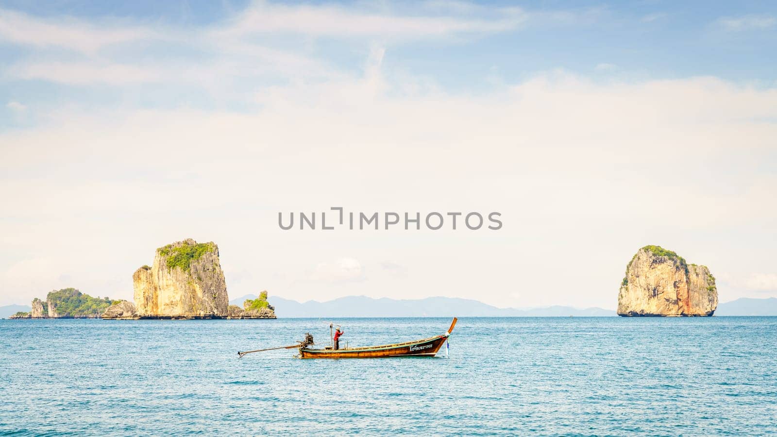 Krabi, Thailand, November 9, 2017: Thai long tail fishing boat in the Andaman Sea with islands and Krabi coastline on the horizon