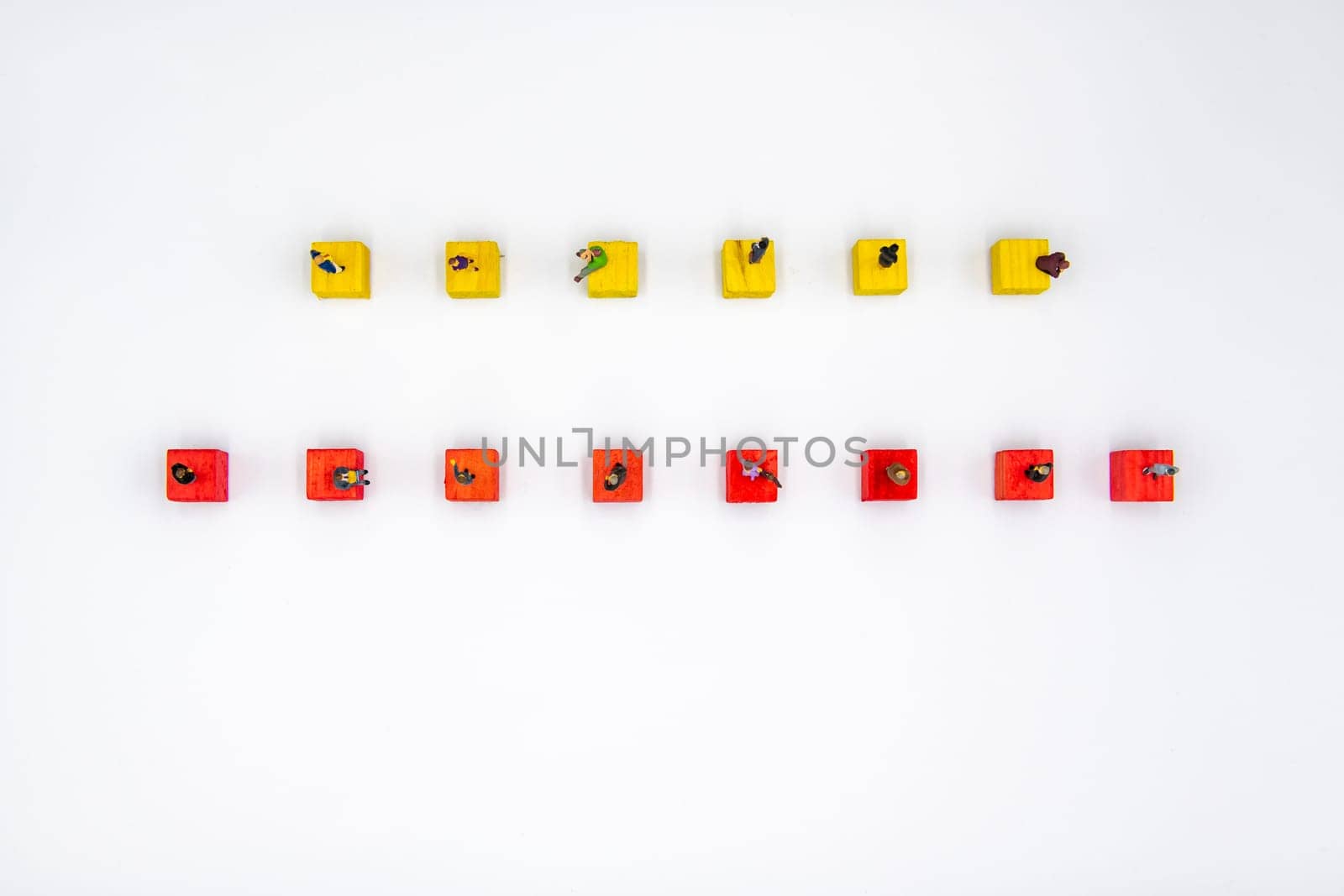 Miniature figurines standing socially distanced on wooden cubes isolated over white background