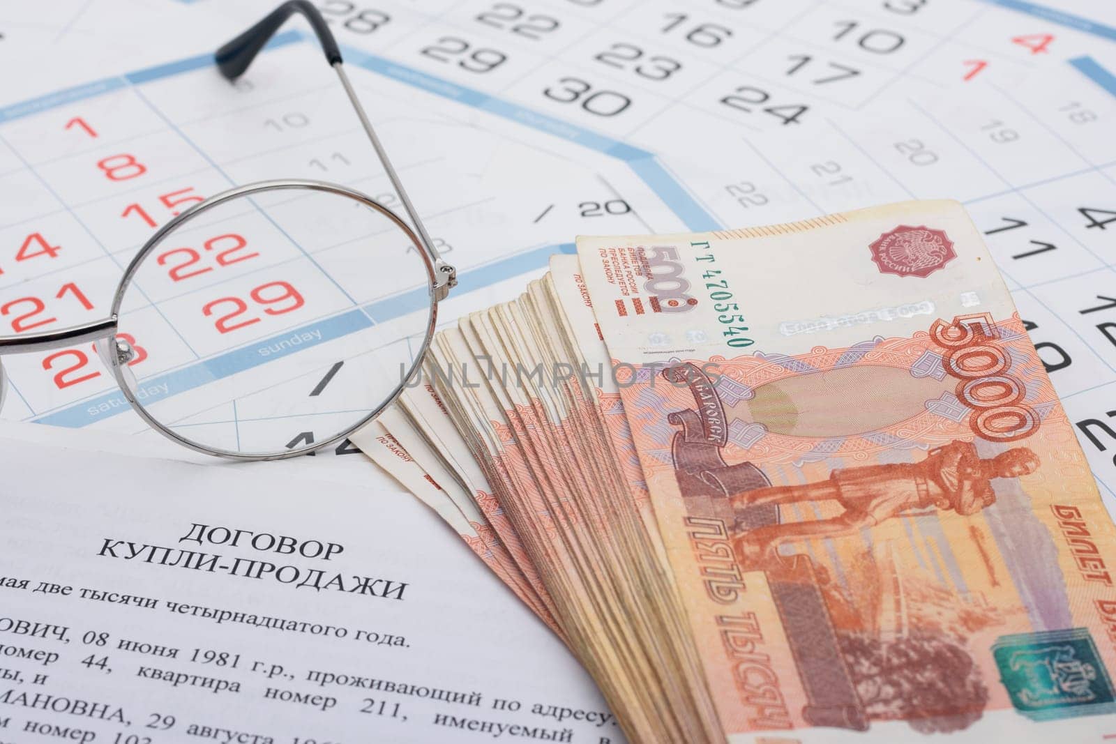 Sale and purchase agreement of an apartment, a wad of money, a calendar and glasses