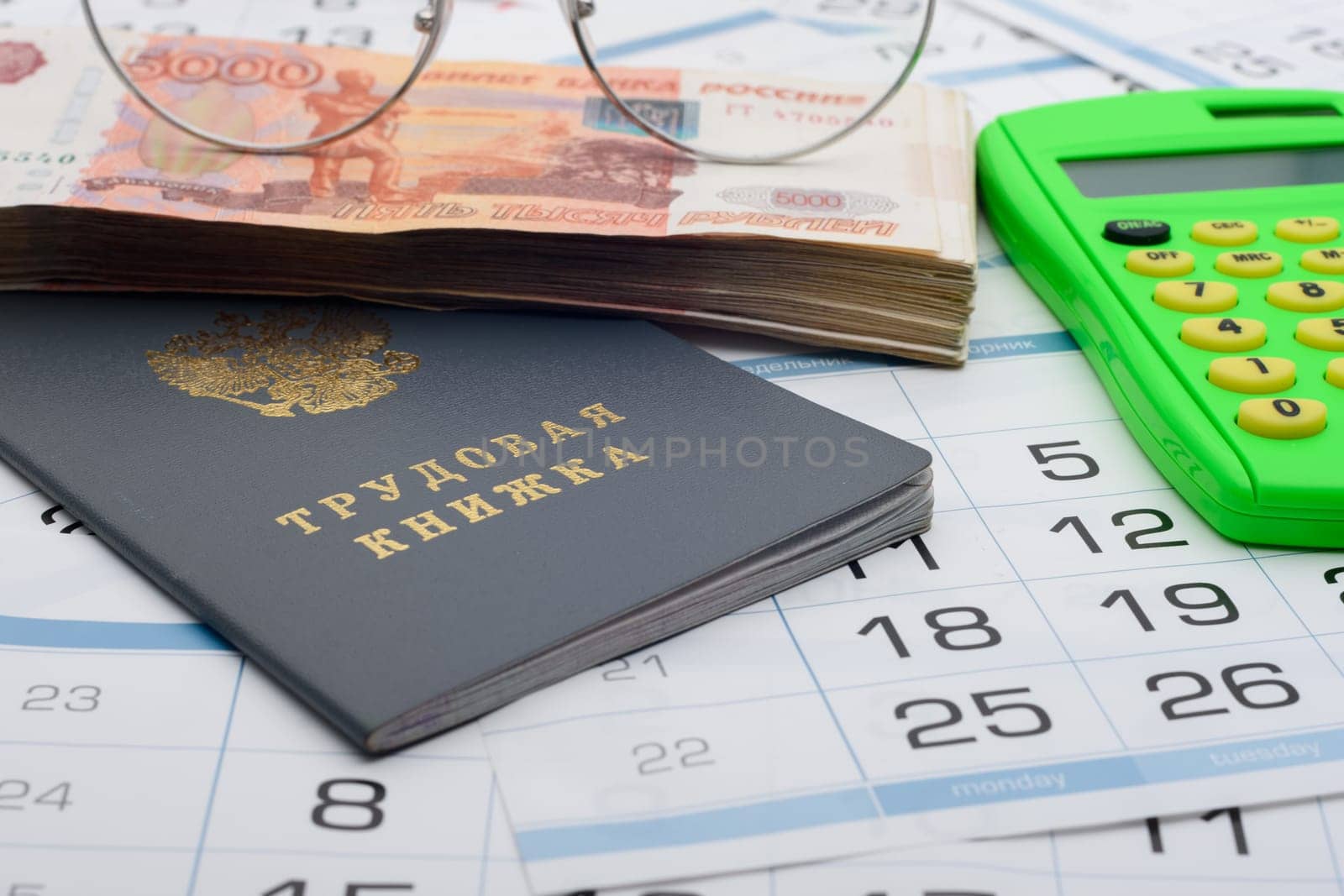 Labor book of the Russian Federation, on it is a bundle of five-thousandth bills, glasses and a calculator