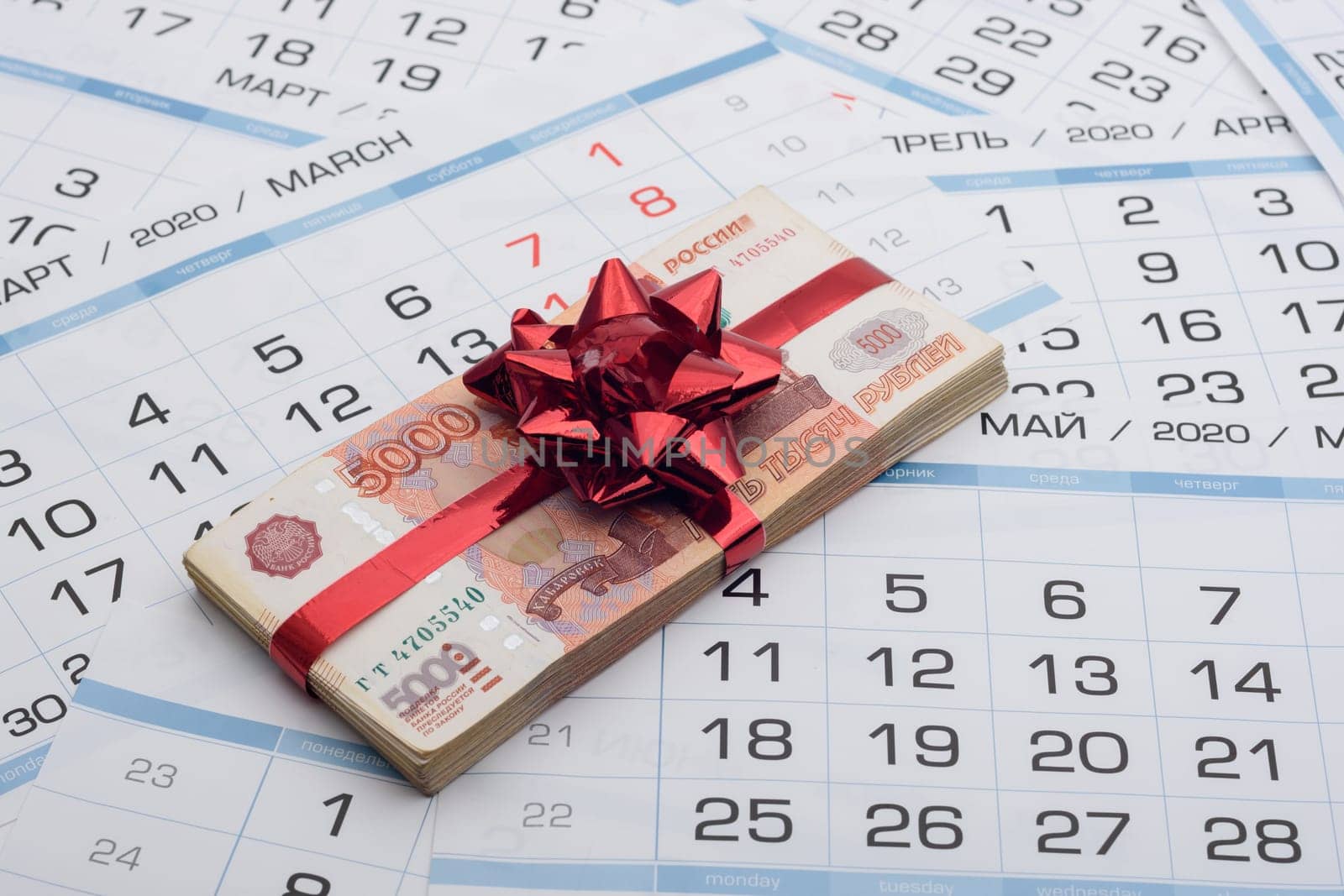 A bundle of Russian five-thousandth bills with a red bow lies on a background from a calendar