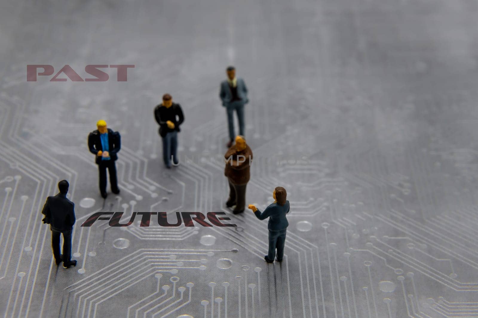 Miniature figurines posed as business people in a meeting over abstract futuristic circuit board with text Past versus Future