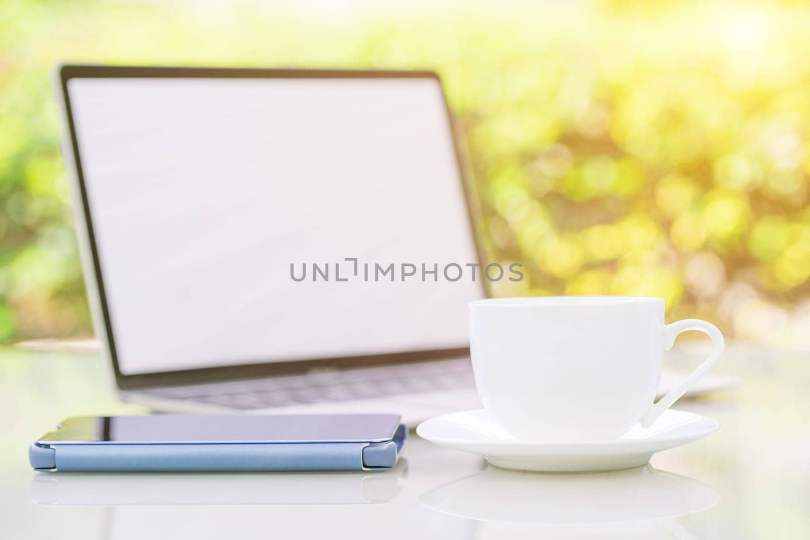 Close up coffee cup and laptop on table at office with smartphone