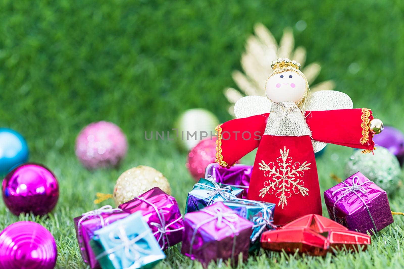 Celebration of New year and Christmas, Christmas angel doll and christmas decoration on green grass background