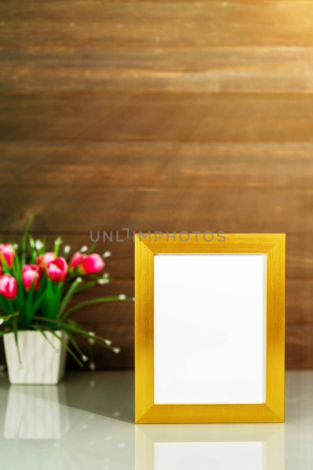 Picture mock up with golden frame and Artificial flower vase bouquet over table with wood wall background