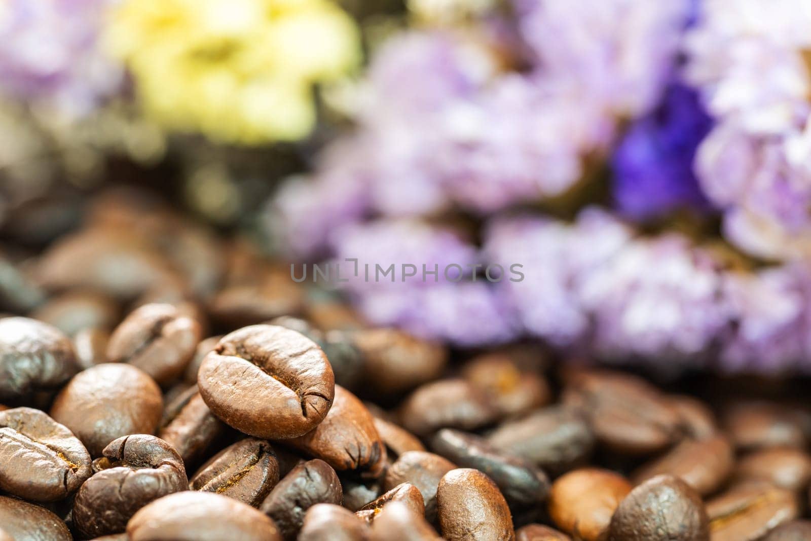 Close up roasted coffee beans heap with flower background