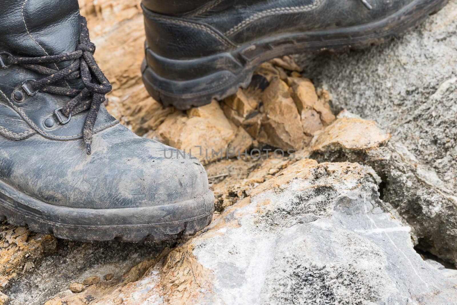 Closeup of trekking leather boot on the rock in mountain