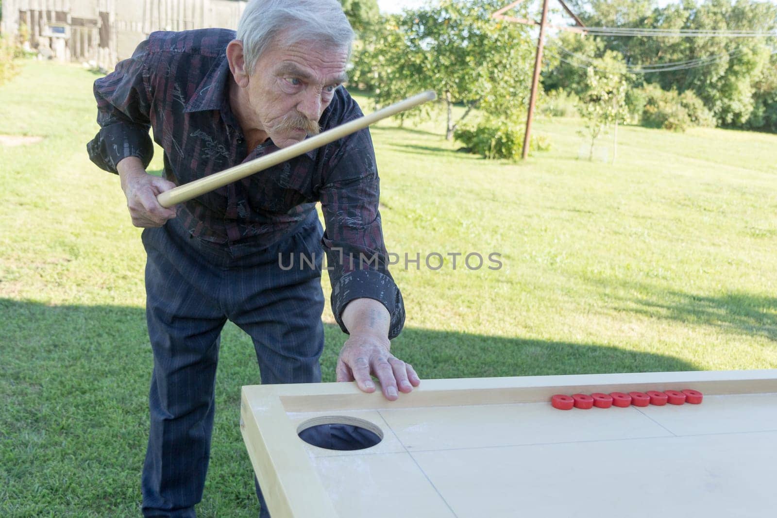Man playing Novuss in outdoors. Novuss is a national sport in Latvia similar to pocket billiards or pool.