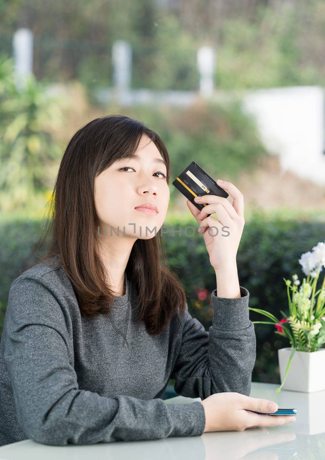 Young woman sitting showing credit card and holding smartphone for online shopping,Online shopping concept