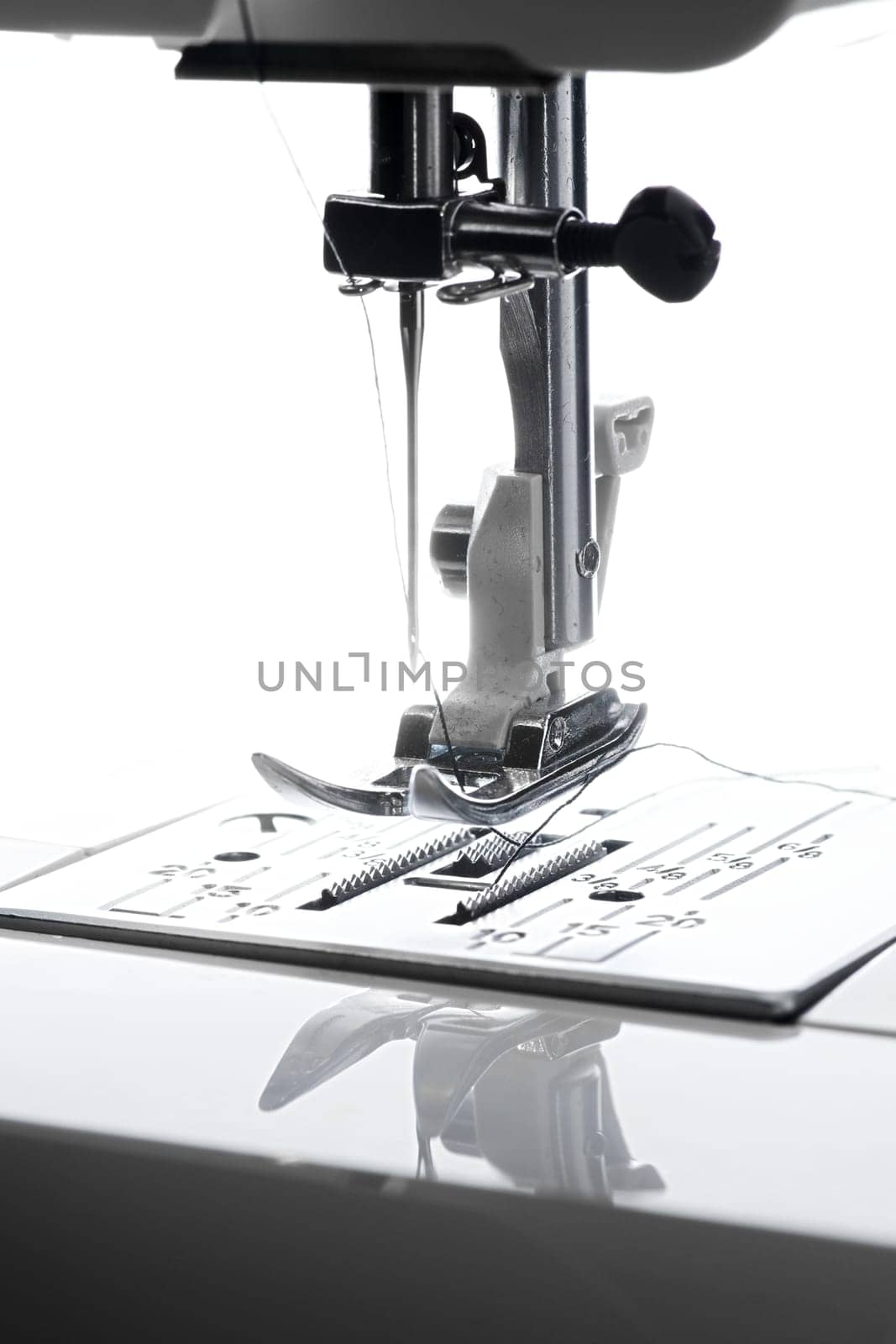 9 - Vertical close up macro image of bright needle and sewing machine working area.