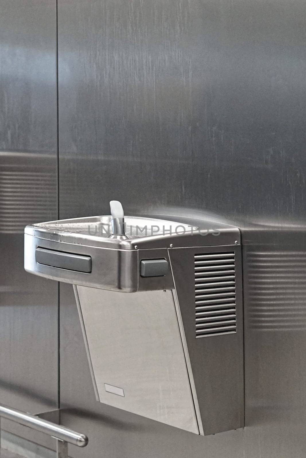 Stainless steel drinking fountain mounted at wall