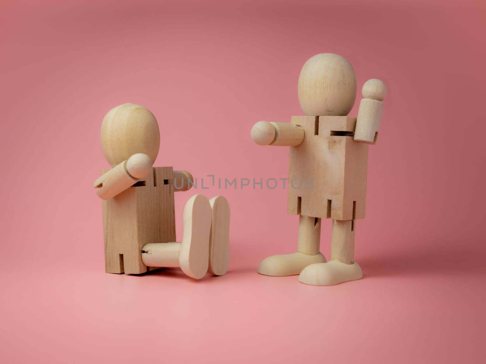 2 wooden dolls sitting and standing Talk gestures On the pink background..Concept of social contact from wood dolls..