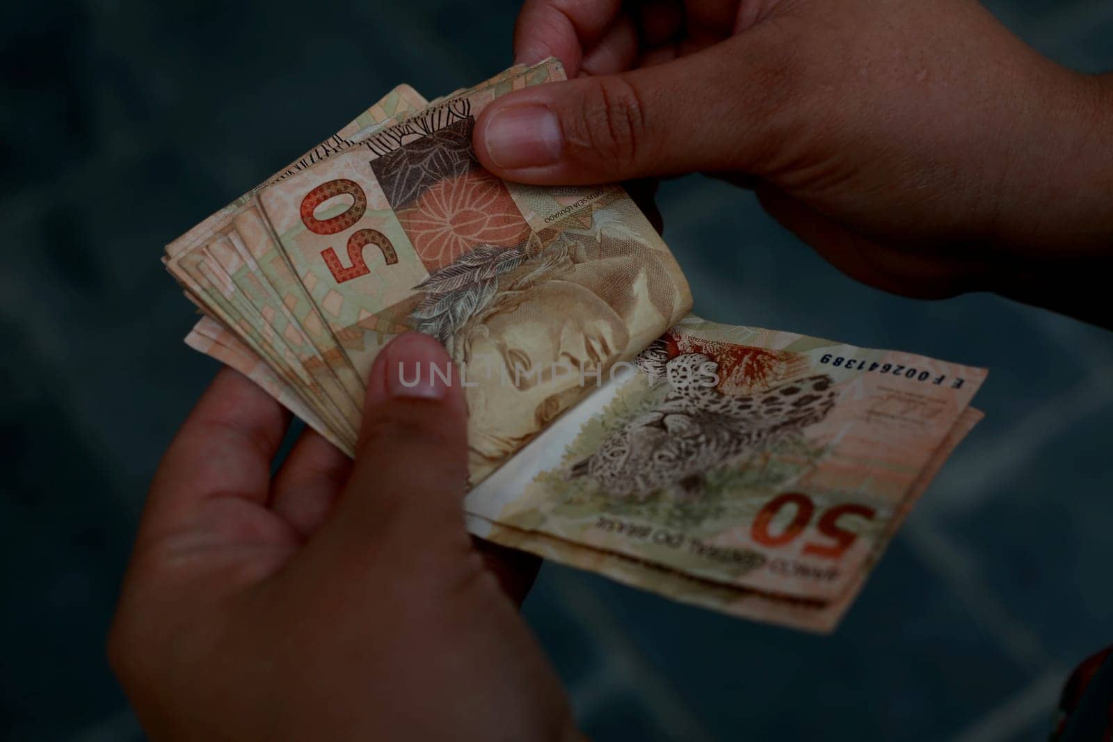 salvador, bahia / brazil - february 25, 2015: hands hold fifty reais (R $ 50.00) bills in the city of Salvador......