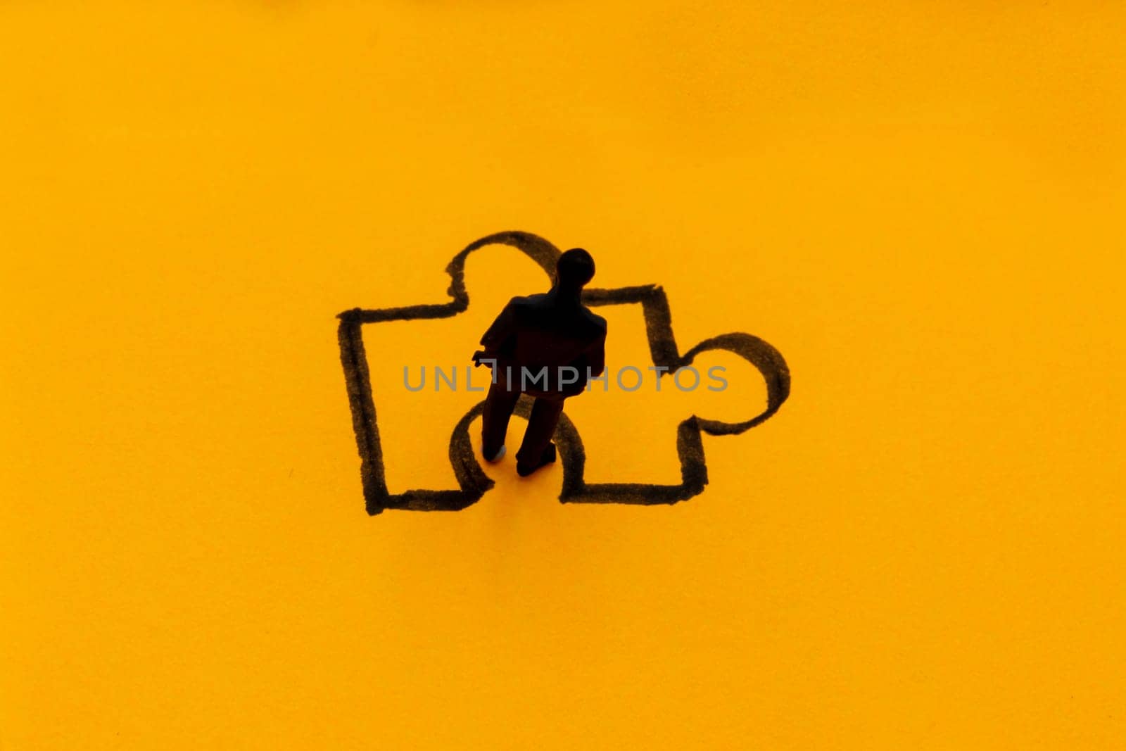 Miniature figurine posed as businessman in front of puzzle piece, solution concept image