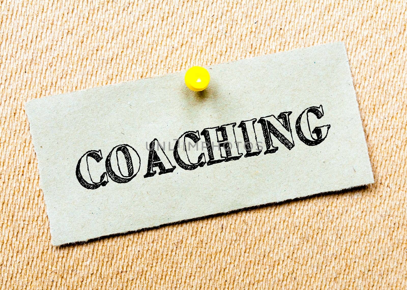 Recycled paper note pinned on cork board.Coaching Message. Concept Image