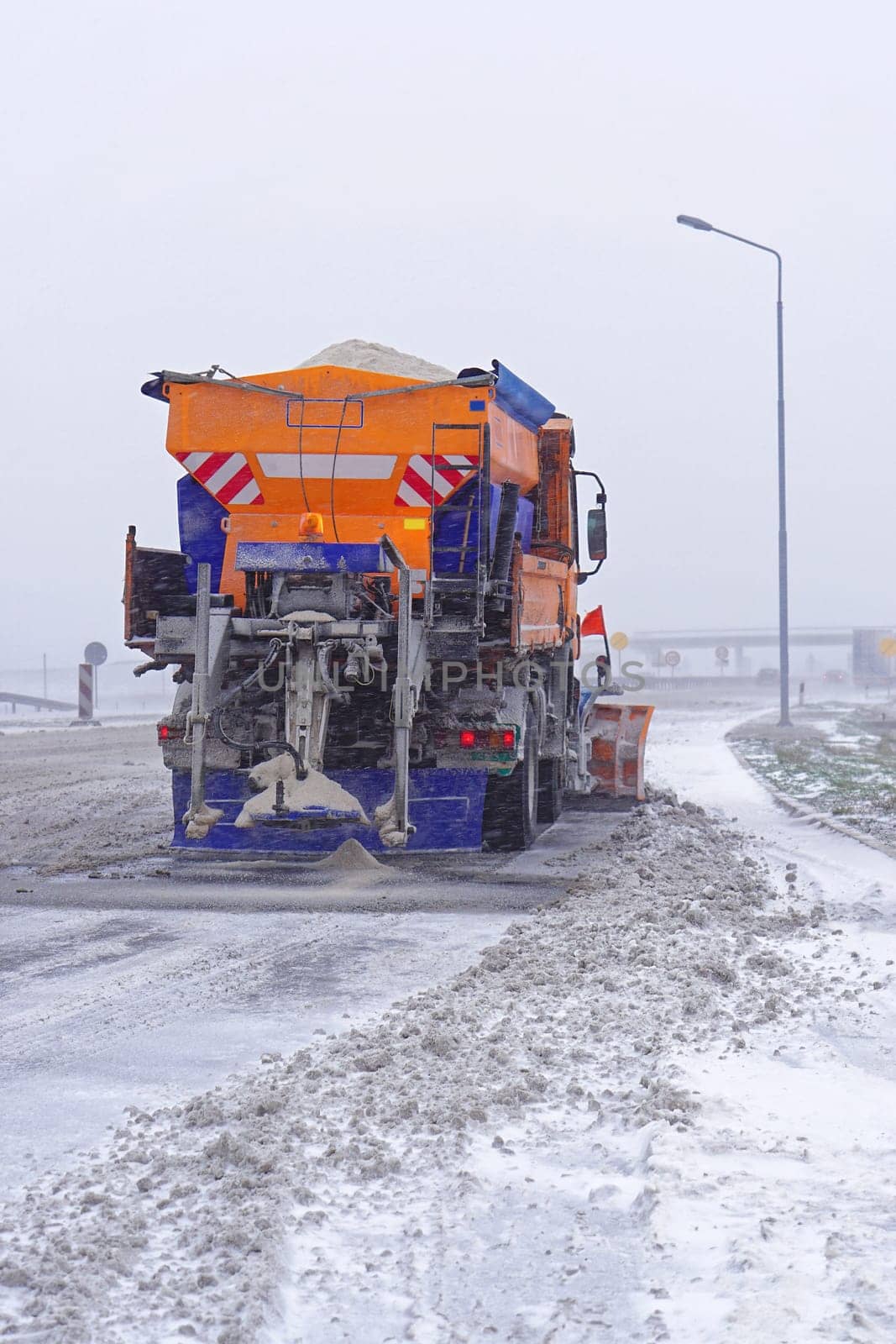 Snowplow truck with salt spreader at highway