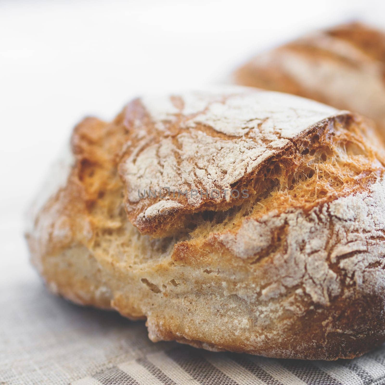 Tasty loaf of bread on table cloth. Extreme close-up of rustic Italian bread. Shallow DOF.