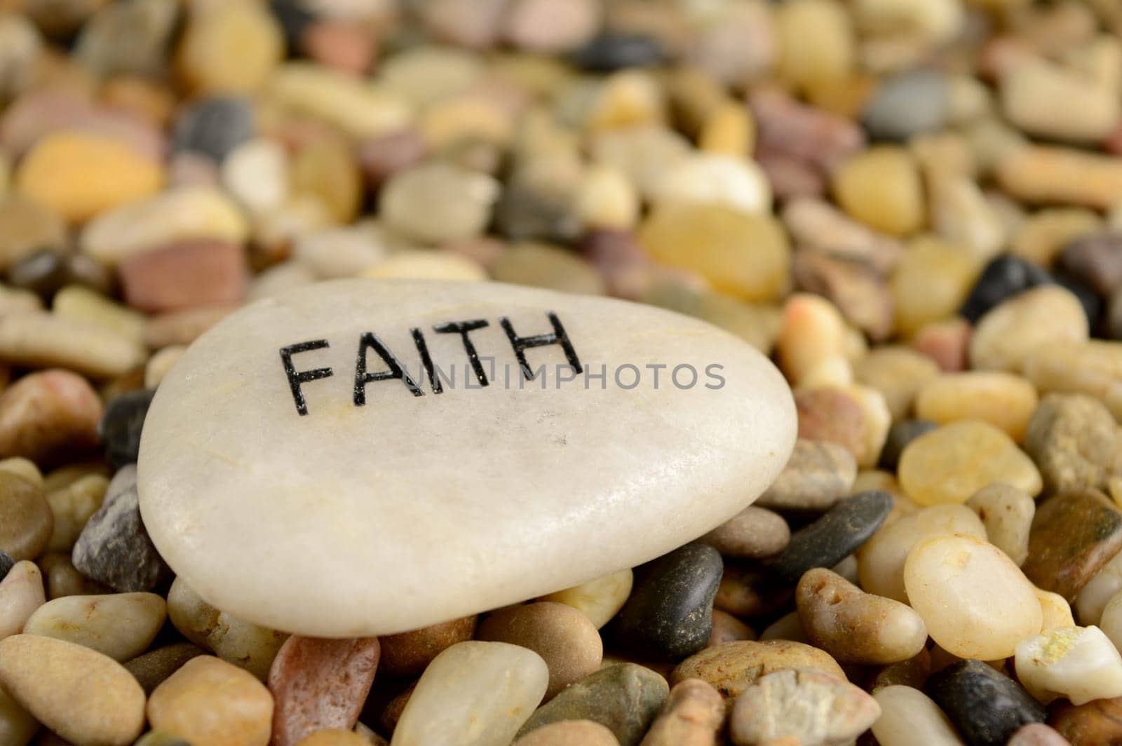 A smooth river stone is etched with the word faith for spiritual affirmation purposes.