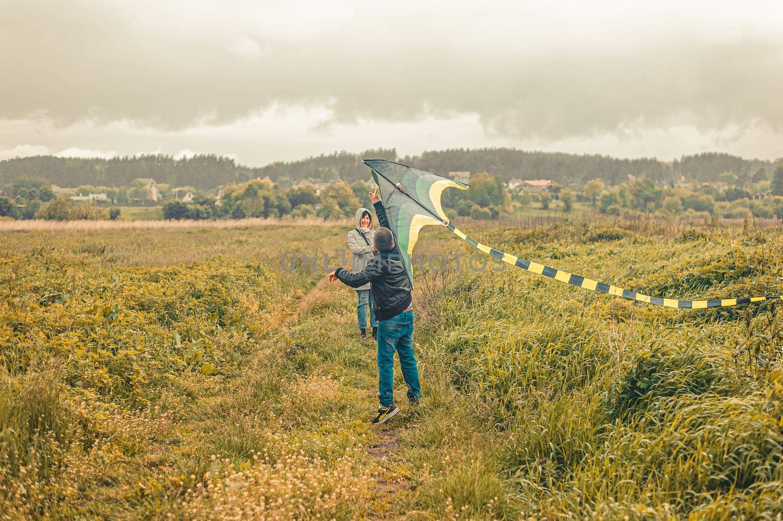 schoolboy and his mother launches a kite into the air in a field