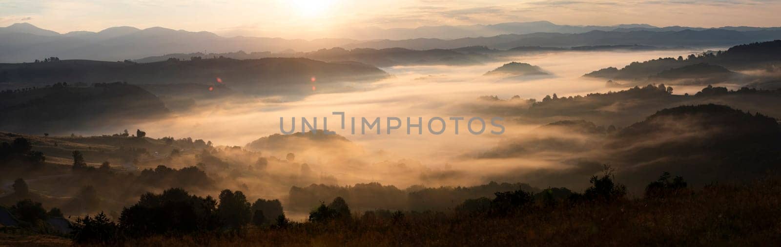Banner of beautiful landscape in the mountains at sunrise. View of foggy hills and valley covered by forest.