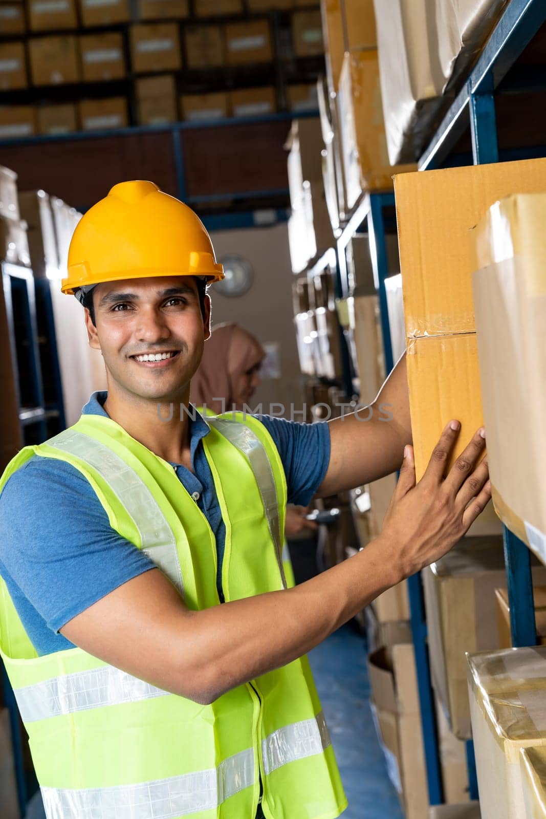 Portrait of Indian warehouse worker put cardboard box in to shelf with muslim asian worker do inventory in warehouse distribution center environment. Using in business warehouse and logistic concept.