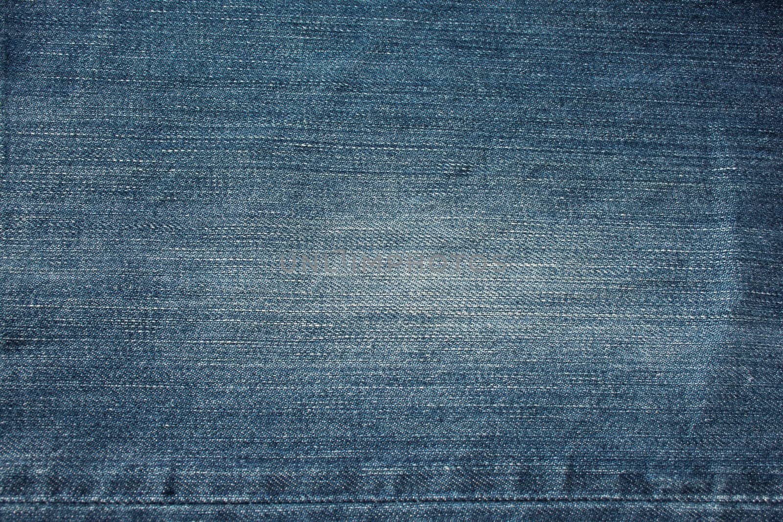 Fragment of blue frayed denim jeans background