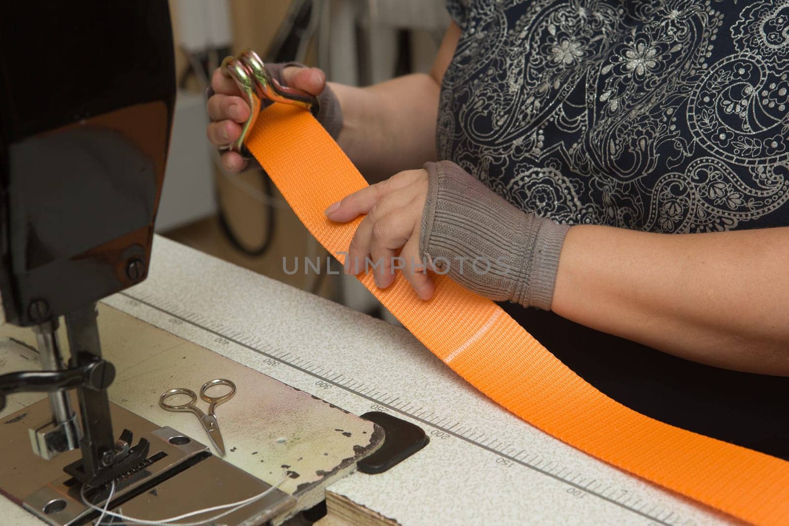 Industrial sewing machine sews a webbing sling. Manufacture of textile slings and tie straps