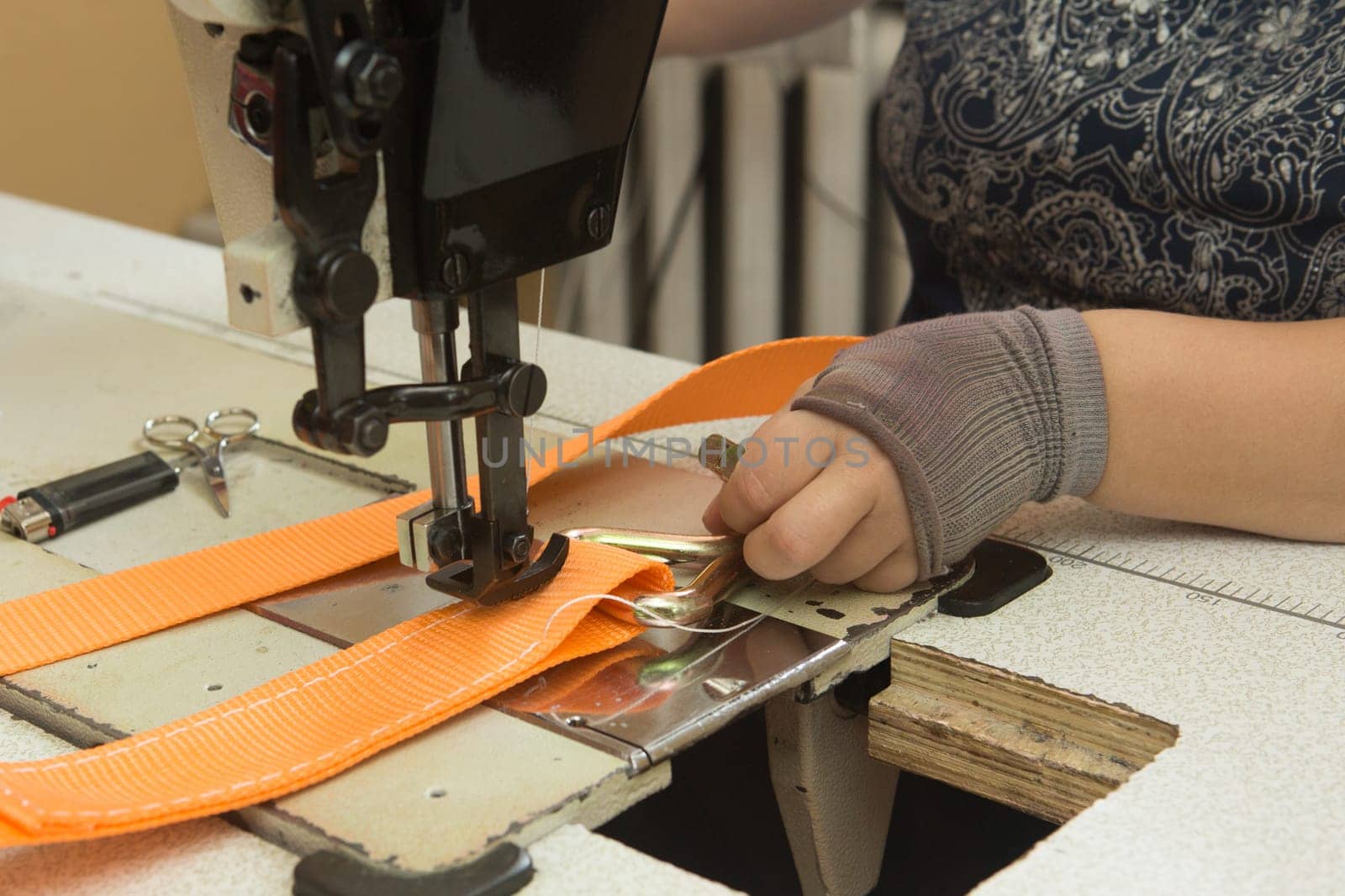 Industrial sewing machine sews a webbing sling. Manufacture of textile slings and tie straps