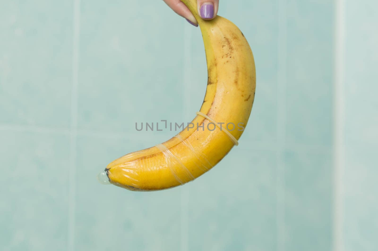 Condom and banana on a blue background close-up.