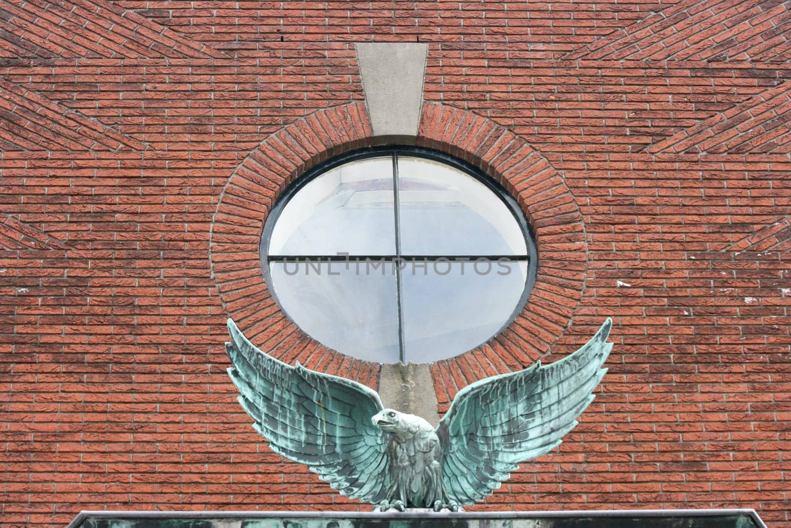a Eagle with outstretched wings in front of a red brick wall