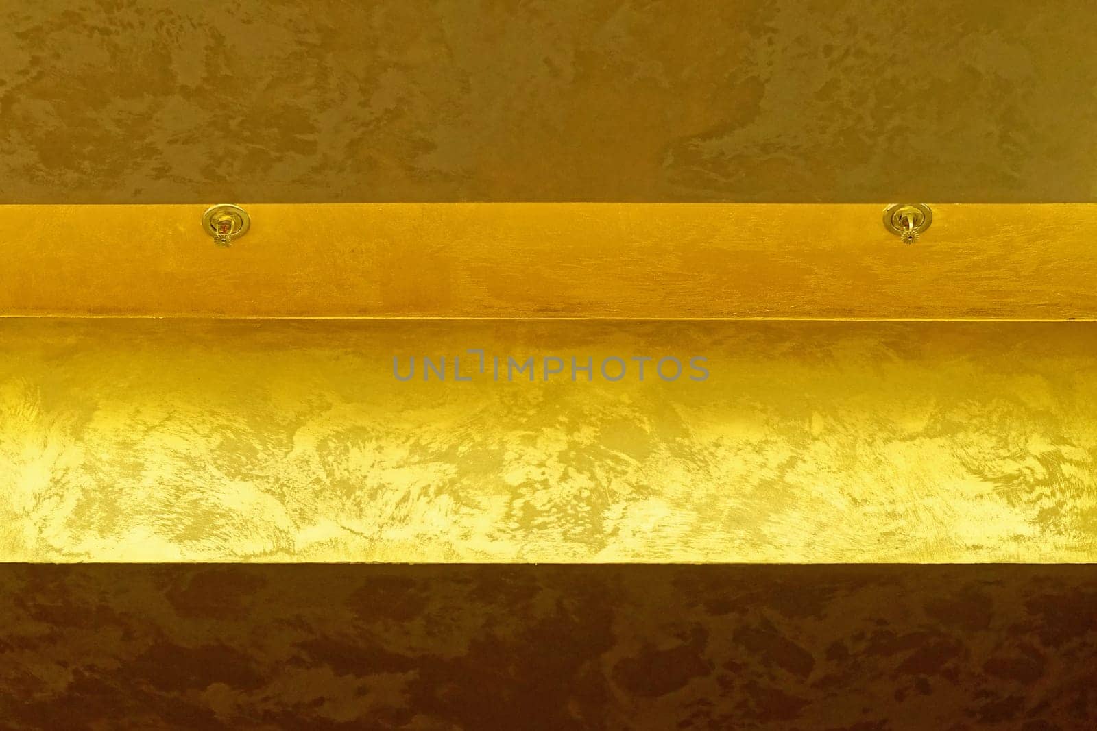 Two fire sprinklers at golden ceiling