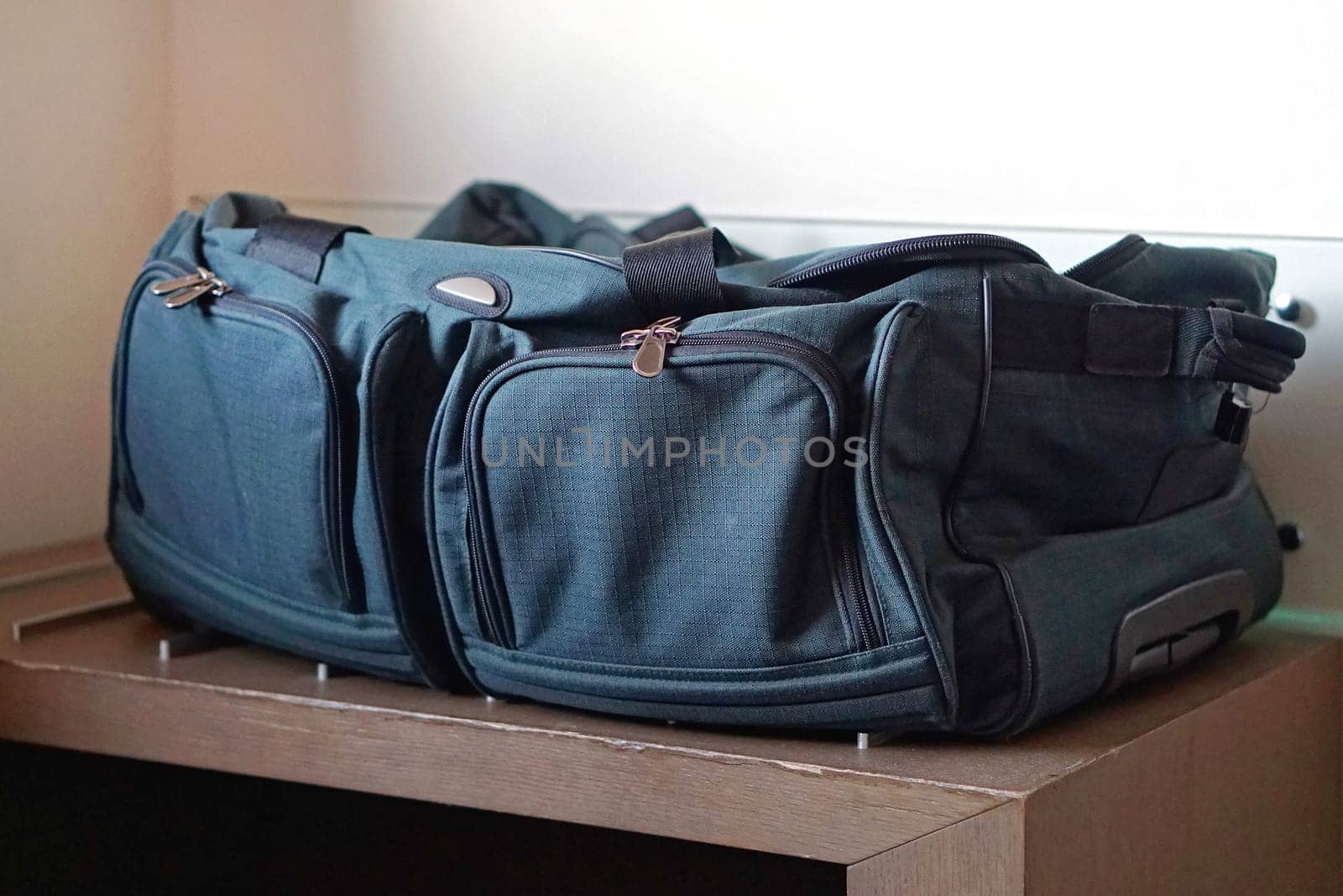 Big green luggage bag at table in room