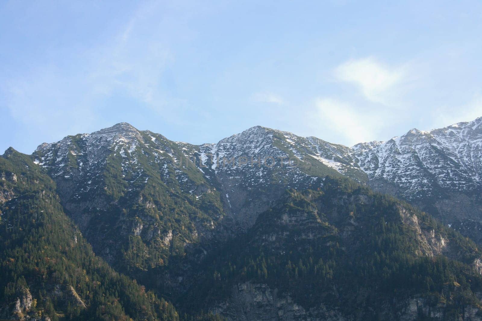 Alpine summits covered with snow, blue sky in the background .