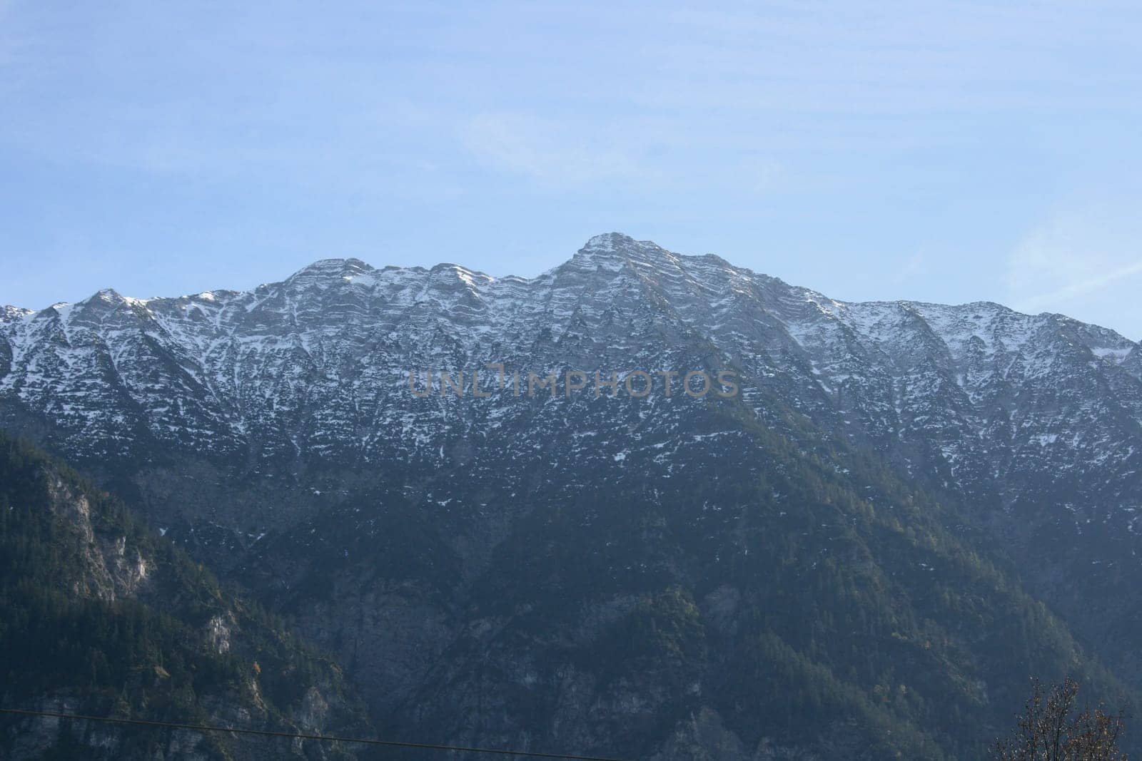 Alpine summits covered with snow, blue sky in the background .