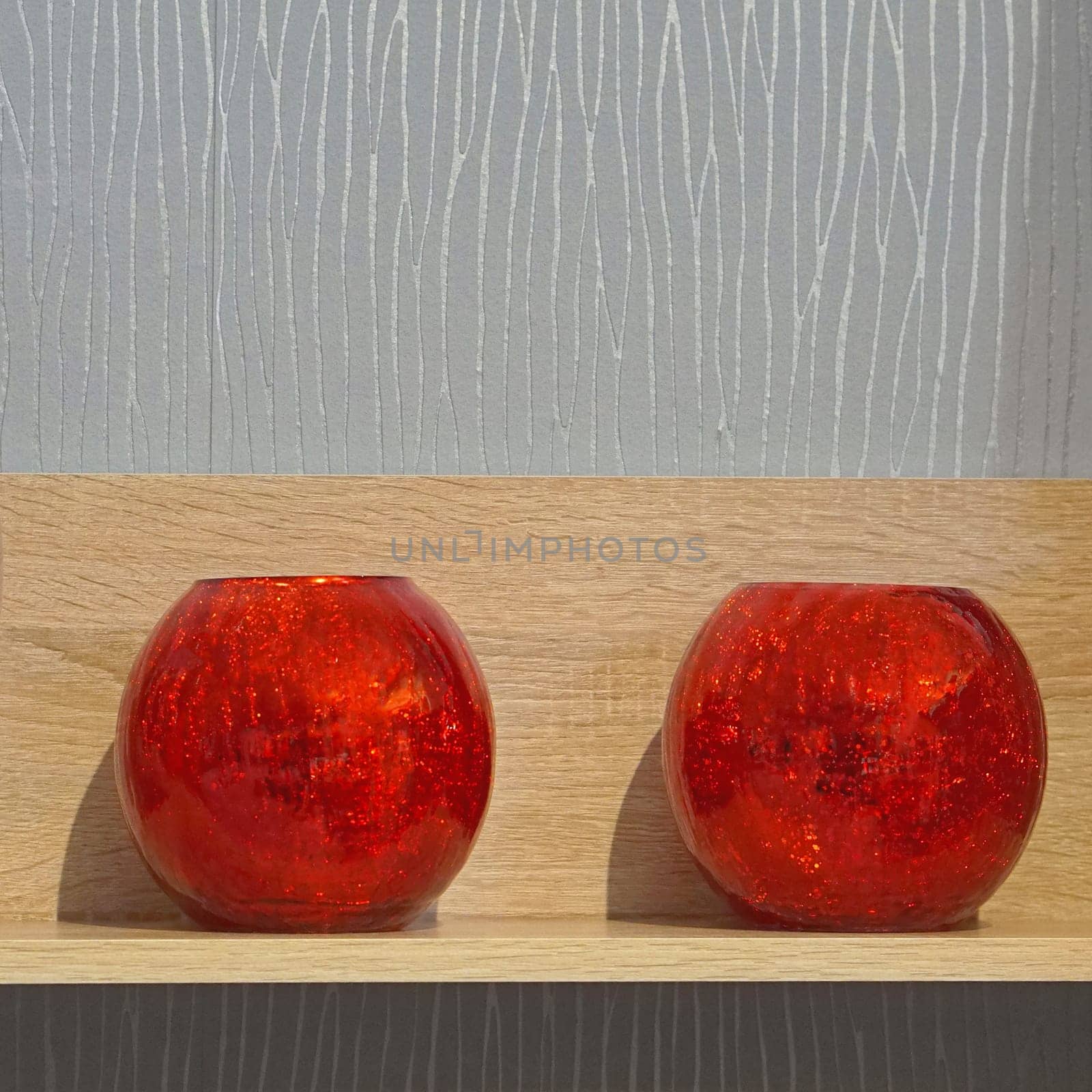 Two scented candles in red glass at shelf