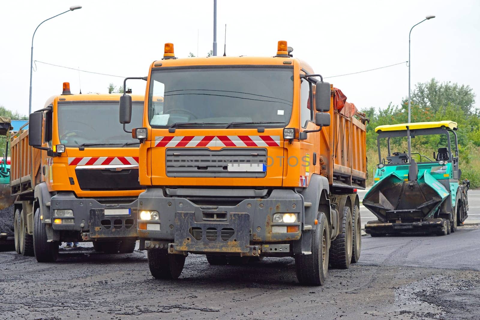 Road works trucks with asphalt and surfacing machine