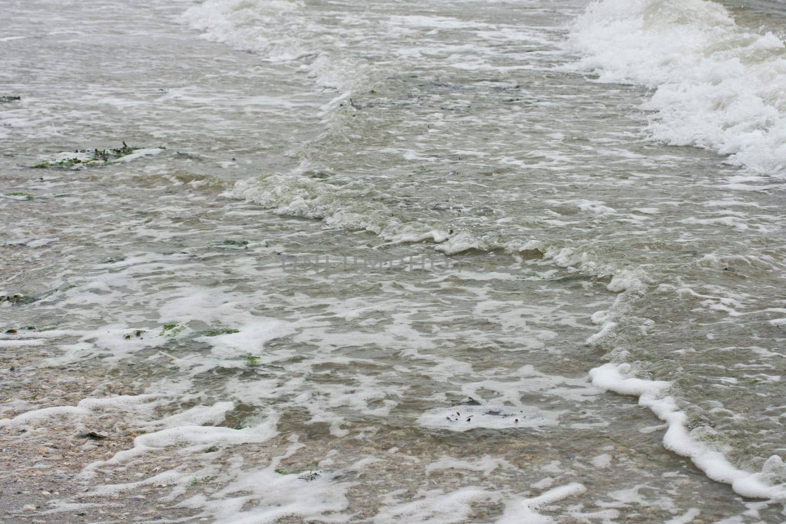Waves with white crests inundate the sandy beach