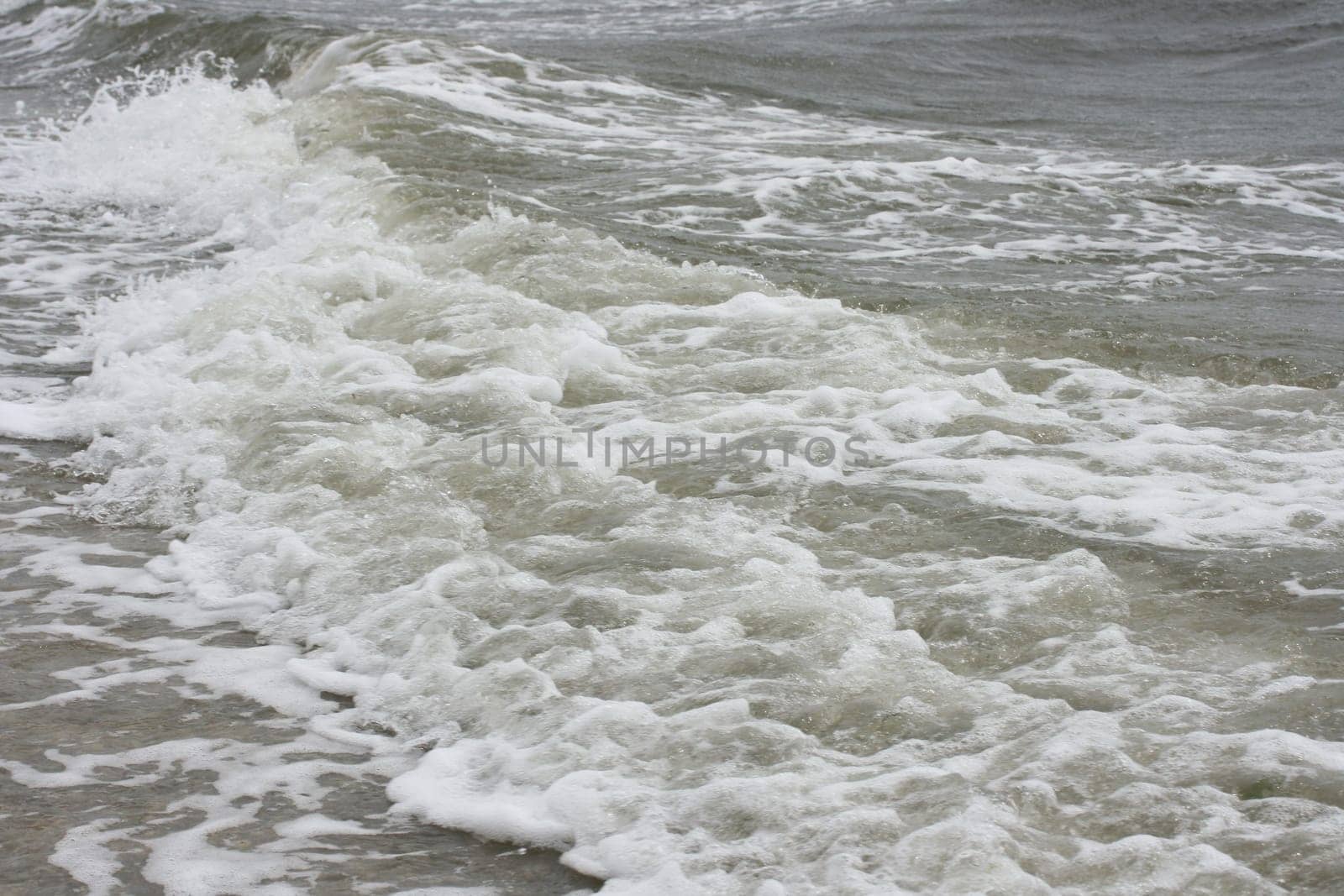 Waves with white crests inundate the sandy beach