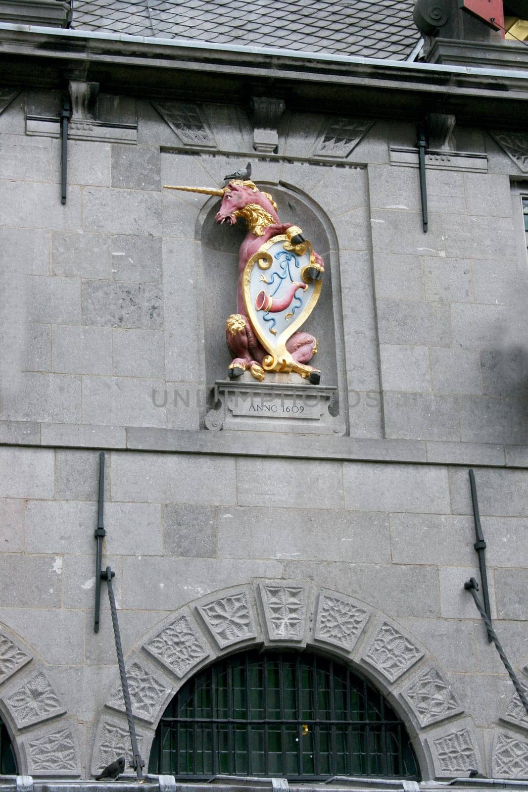Crest with Unicorn, grey stone wall in the background .