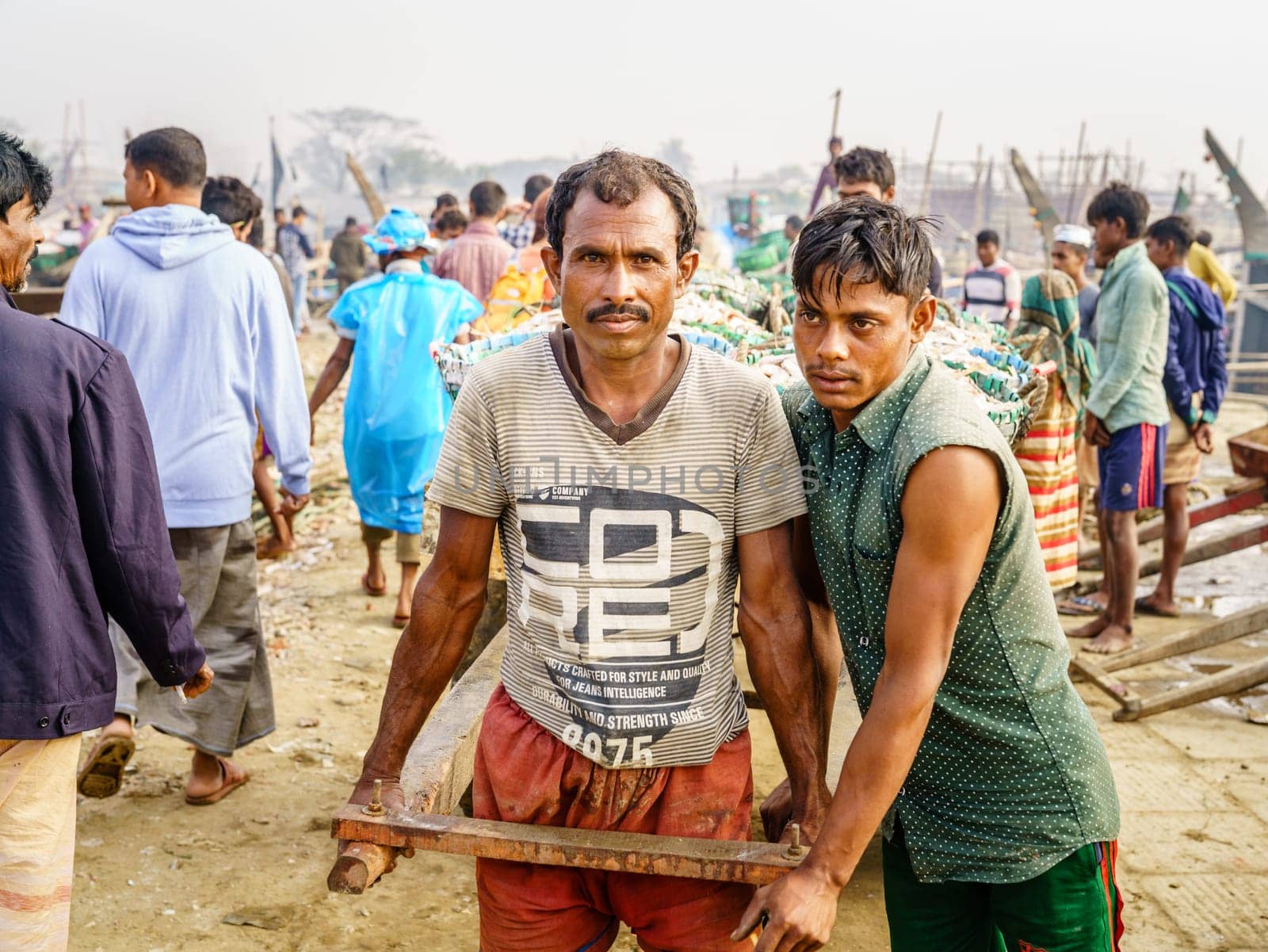 Chittagong, Bangladesh, December 23, 2017: Portrait of fishermen pulling cart with fresh catch of shrimp