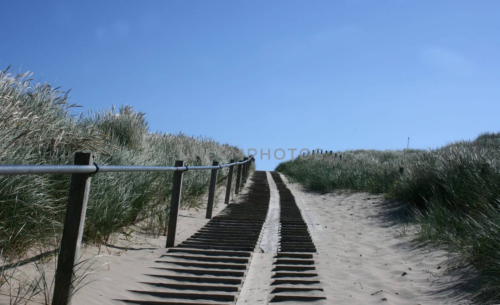 A steep climb up a dune, blue sky in the background