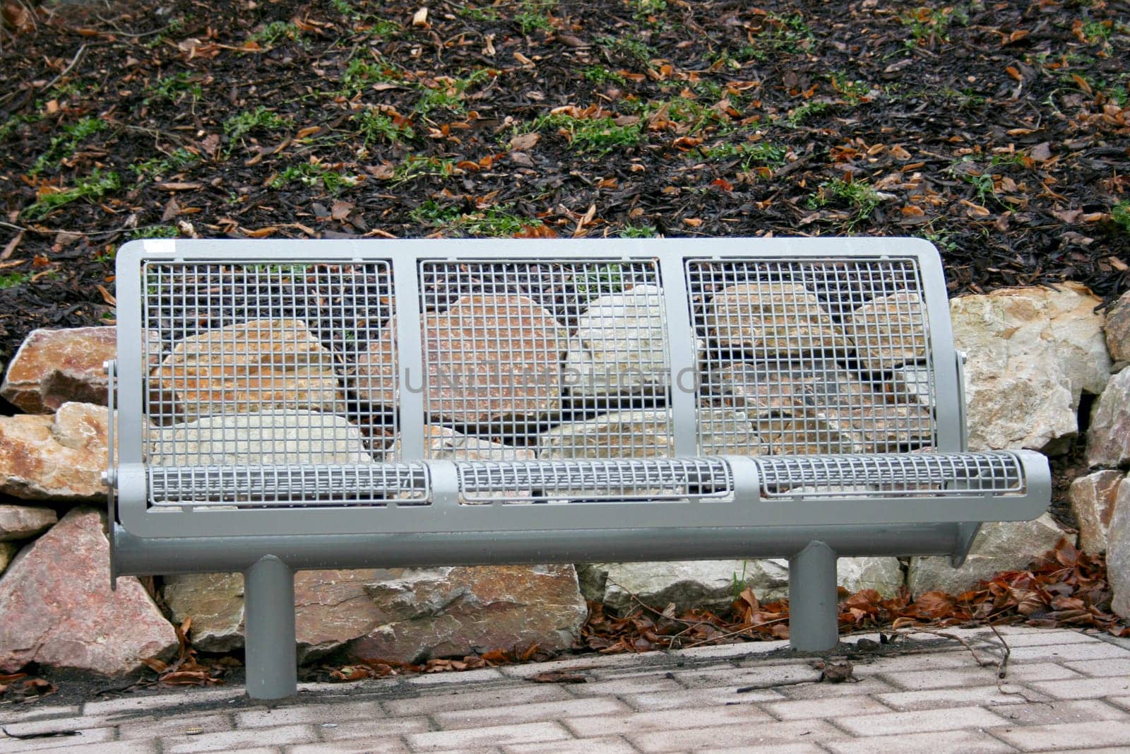 An iron resting bench in front of large natural stones.